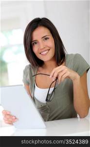 Smiling young woman working on electronic tablet at home