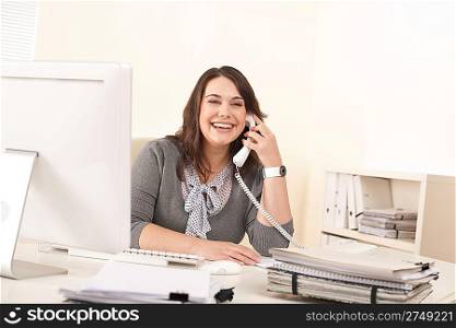 Smiling young woman working on the phone at office