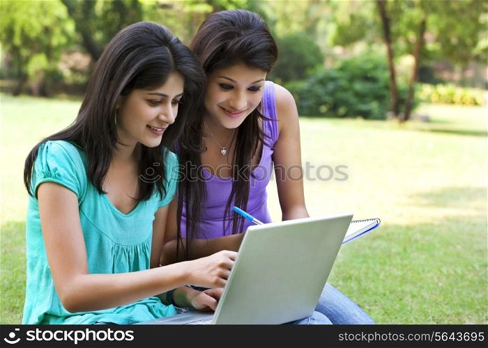 Smiling young women taking notes from laptop