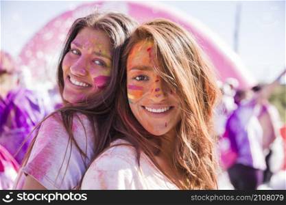 smiling young women with holi color their face standing back back