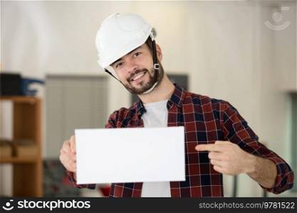 smiling young worker pointing to a white placard ready text