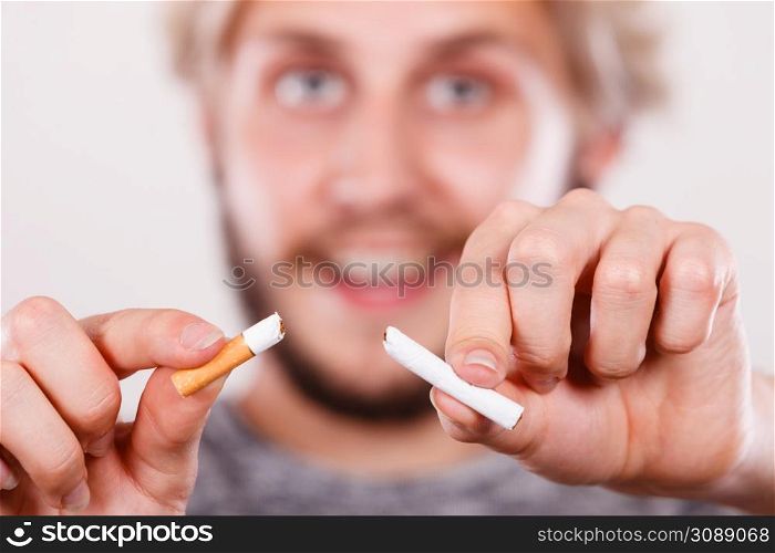 Smilling man breake down cigarette. Winning with addicted nicotine problems, stop smoking. Quitting from addiction concept.. Smilling man is breaking a cigarette