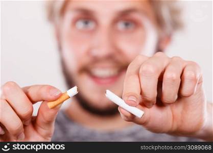 Smilling man breake down cigarette. Winning with addicted nicotine problems, stop smoking. Quitting from addiction concept.. Smilling man is breaking a cigarette