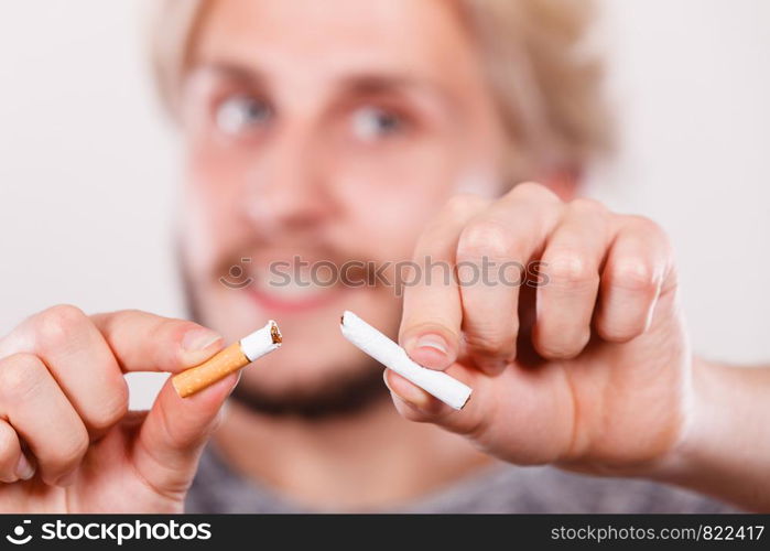 Smilling man breake down cigarette. Winning with addicted nicotine problems, stop smoking. Quitting from addiction concept.. Smilling man is breaking a cigarette