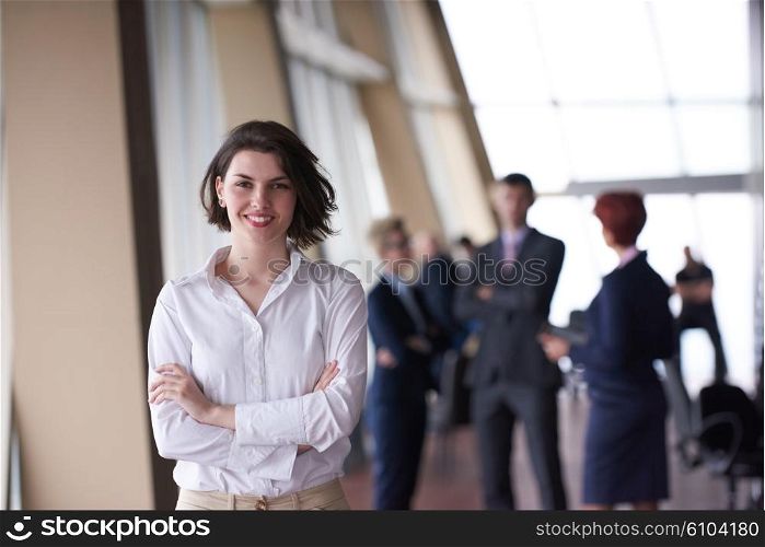 Smilling young business woman in front her team blured in background. Group of young business people. Modern bright startup office interior.