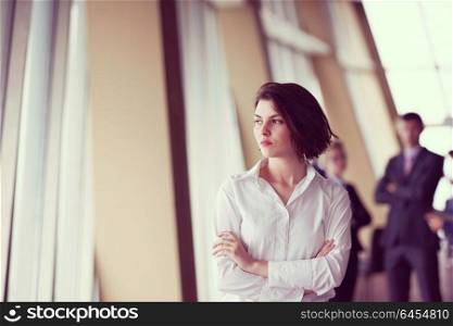 Smilling young business woman in front her team blured in background. Group of young business people. Modern bright startup office interior.