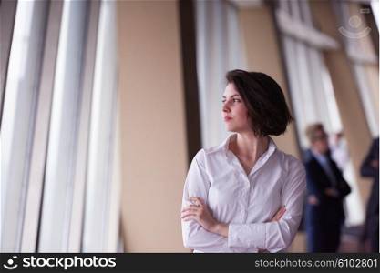Smilling young start up business woman in front her team blured in background. Group of young business people. Modern bright startup office interior.