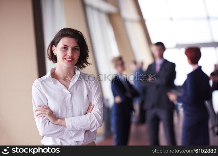 Smilling young start up business woman in front her team blured in background. Group of young business people. Modern bright startup office interior.