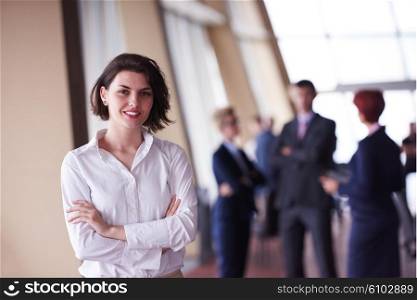 Smilling young start up business woman in front her team blured in background. Group of young business people. Modern bright startup office interior.