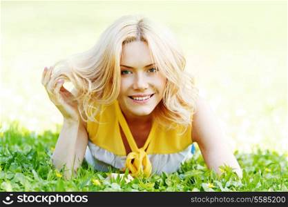 Smilng happy young woman lying on green grass meadow