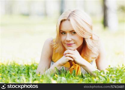 Smilng happy young woman lying on green grass meadow