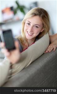 Smilng woman showing smartphone towards camera