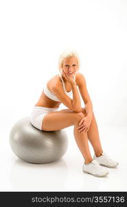 Smily blonde sitting on silver pilates ball on white background