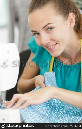 smily young woman sewing with sewing machine