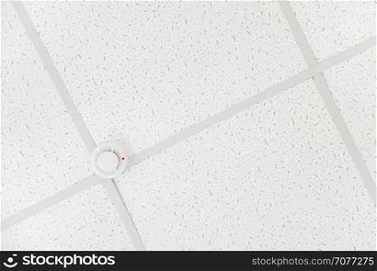Smoke detector of fire alarm on the background of a white ceiling