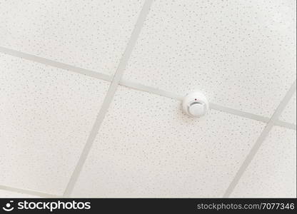 Smoke detector of fire alarm on the background of a white ceiling