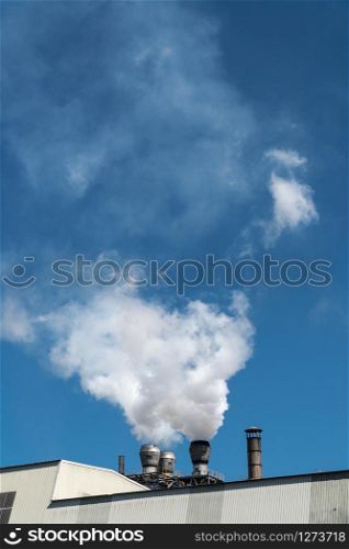 Smoke emission from factory pipes on blue sky