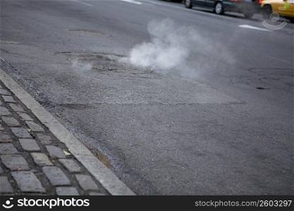 Smoke emitting from a manhole on the road