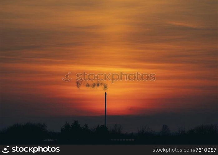 Smoke from a chimey in a beautiful sunset with industrial silhouettes