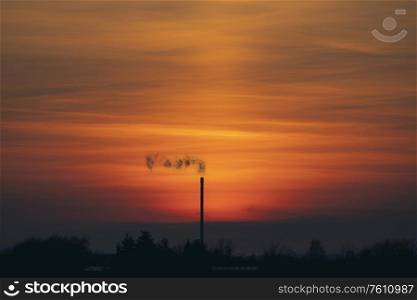 Smoke from a chimey in a beautiful sunset with industrial silhouettes