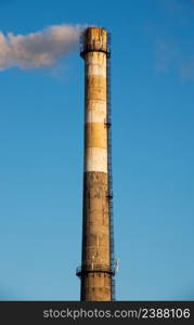 Smoke from a chimney on blue sky background