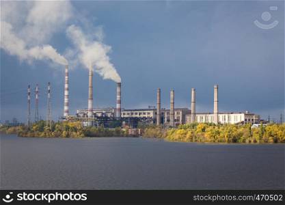 smoke from the chimney of power plant on a river bridge