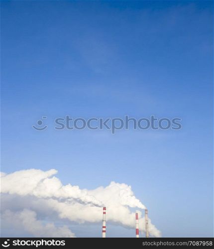 smoke from the chimney of the plant on the background of a clear blue sky, landscape per day. smoke from the chimney
