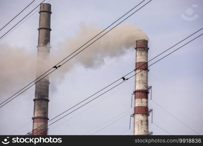 Smoke from two industrial chimneys, pipes, against the sky. Global warming. Air pollution. Ecological pollution. Air emissions polluting the city. Industrial waste is hazardous to health. Smoke from two industrial chimneys, pipes, against the sky. Global warming. Air pollution. Ecological pollution. Air emissions polluting the city. Industrial waste is hazardous to health.