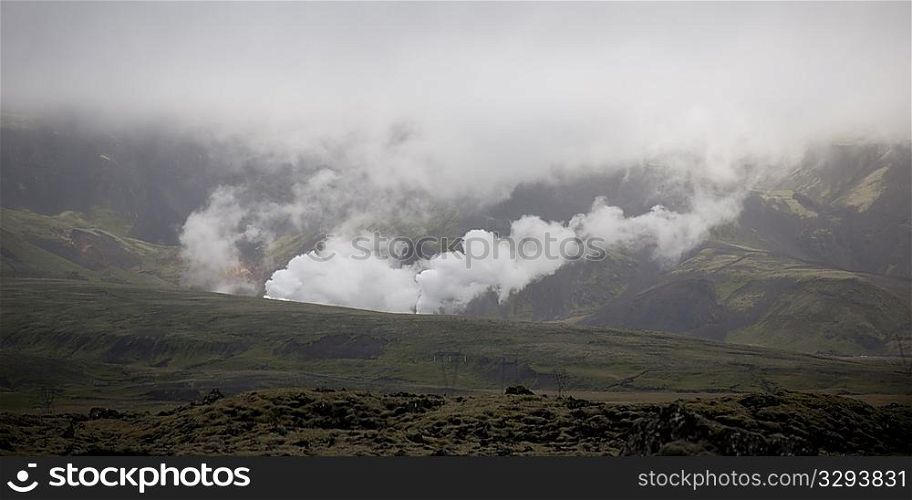 Smoke rising from valleys into clouded mountains