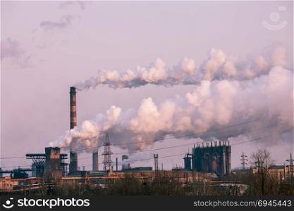 smoke stacks in a working factory emitting steam, smog and air pollution.