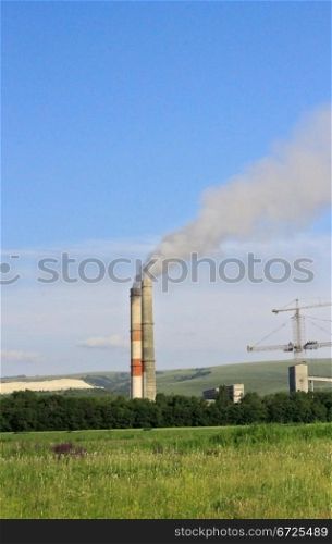 Smoke stacks of cement factory. Summertime landscape