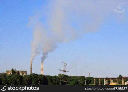 Smoke stacks of cement factory. Summertime landscape
