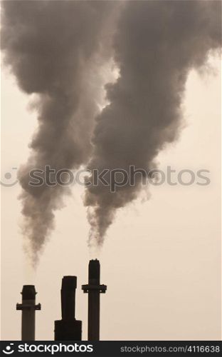 Smoke stacks pumping out pollution in golden evening light.
