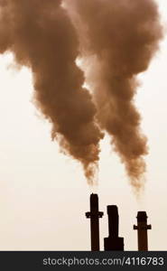 Smoke stacks pumping out pollution in golden evening light.