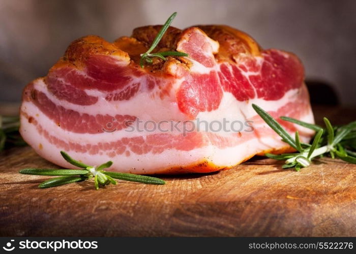 Smoked bacon with rosemary on wooden table