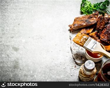 Smoked barbecue ribs with beer and herbs. On a stone background.. Smoked barbecue ribs with beer and herbs.