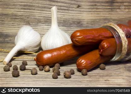Smoked beer sausage with garlic and spices on wooden background.