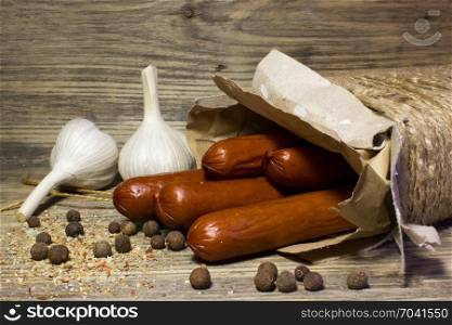 Smoked beer sausage with garlic and spices on wooden background.