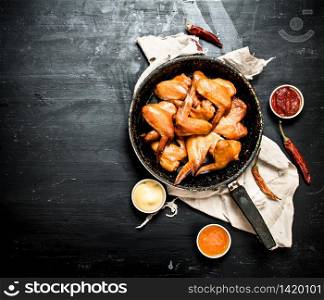Smoked chicken wings in the pan with the sauce. On black chalkboard.. Smoked chicken wings in the pan with the sauce