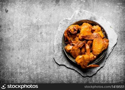 Smoked chicken wings. On a stone background.. Smoked chicken wings.