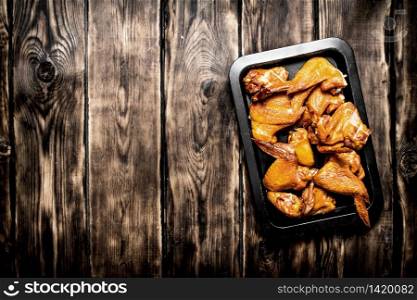 Smoked chicken wings on the baking sheet. On a wooden table.. Smoked chicken wings