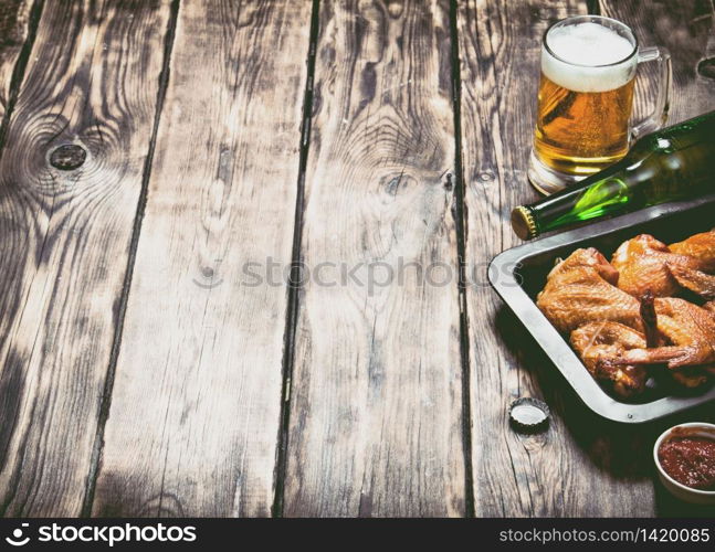 Smoked chicken wings with beer and sauce. On a wooden table.. Smoked chicken wings with beer