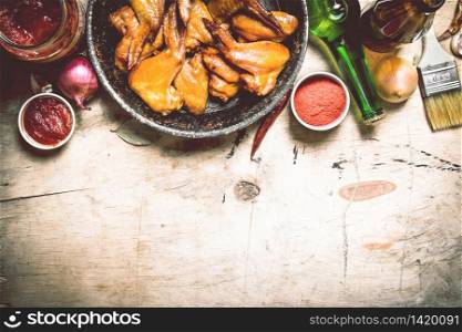 Smoked chicken wings with beer and sauce. On a wooden table.. Smoked chicken wings with beer
