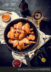 Smoked chicken wings with beer. On black chalkboard.. Smoked chicken wings with beer
