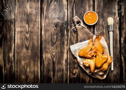 Smoked chicken wings with sauce. On a wooden table.. Smoked chicken wings