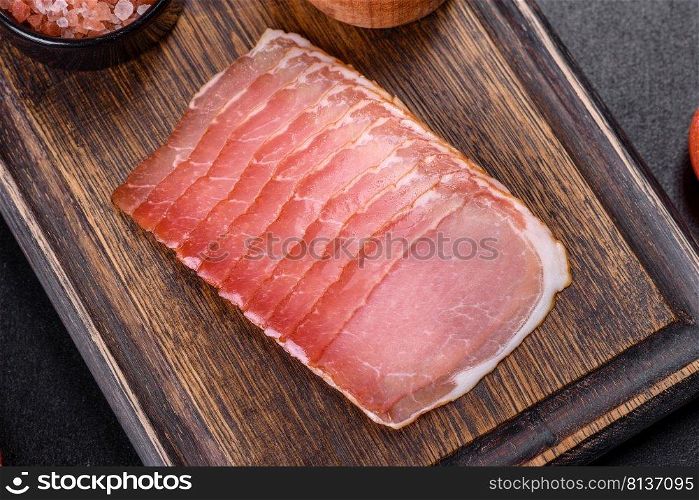 Smoked ham on a dark concrete table with addition of fresh aromatic herbs and spices, natural product from organic farm. Smoked ham on a dark concrete table with addition of fresh aromatic herbs and spices