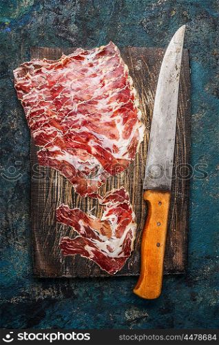 Smoked pork meat from coppa with kitchen knife on rustic wooden background. Traditional Italian specialty made from pork neck . Top view