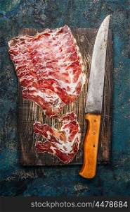 Smoked pork meat from coppa with kitchen knife on rustic wooden background. Traditional Italian specialty made from pork neck . Top view