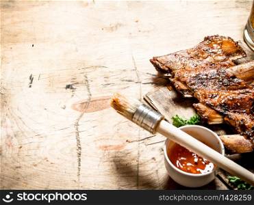 Smoked pork ribs with hot sauce and a brush. On wooden background.. Smoked pork ribs with hot sauce and a brush.