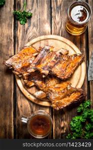 Smoked ribs grilled with beer and parsley. On a wooden table.. Smoked ribs grilled with beer and parsley.